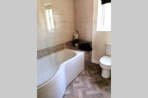 a bathroom with a white tub and a toilet at Clement's Retreat on the North Norfolk Coast in Cromer +9 photos