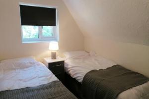 two beds in a room with a lamp and a window at Clement's Retreat on the North Norfolk Coast in Cromer
