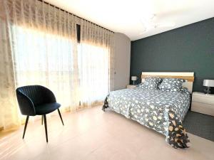 a bedroom with a bed and a chair next to a window at Casa Dani in L'Ampolla +17 photos
