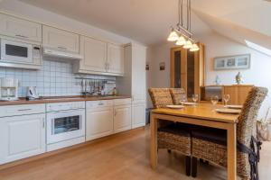 a kitchen with white cabinets and a wooden table with chairs at Ferienwohnung-7-Auszeit-in-der-Villa-Annabelle in Binz