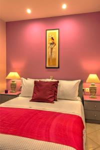 a bedroom with a red wall with a bed and two lamps at Heraklion Beach Hideaway Explore, Relax, Repeat-3 in Ayía Marína