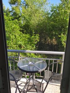 una mesa y sillas en un balcón con árboles en Filio Sevastatou Rooms, en Therma