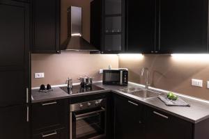 a kitchen with black cabinets and a sink and a microwave at Appartamento zio Primo in Castel San Pietro Terme