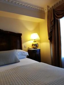 a bedroom with a bed with a lamp and a window at Foley's Townhouse Killarney in Killarney