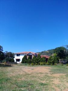 a house with trees in front of a field at Finca Casa Loma Barichara in Barichara