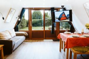 a living room with a couch and a tv at Nurdachhaus Marie im Nordschwarzwald in Neuhausen