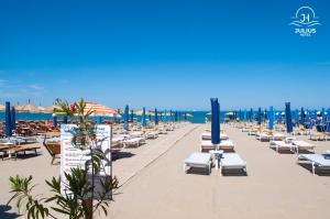 una playa con sillas y sombrillas y el océano en Julius Hotel, en Golem