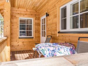 a wooden cabin with a table and chairs on the porch at Holiday Home Kaitaranta by Interhome in Kyyrö