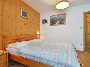 a bedroom with a bed and a wooden wall at Apartment Tieja de Gotart-3 by Interhome in Vigo di Fassa