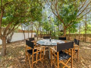 einen Tisch und Stühle in einem Garten mit Bäumen in der Unterkunft Villa Can Jeroni by Interhome in Alcúdia