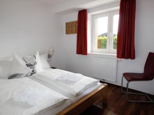 Schlafzimmer mit einem weißen Bett und einem roten Fenster in der Unterkunft Apartment Tom & Jeri by Interhome in Kaprun