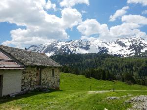 una casa en una colina con montañas cubiertas de nieve en el fondo en Holiday Home Rustico Dolomia by Interhome en Acquacalda