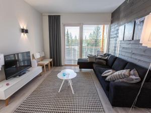 a living room with a black couch and a tv at Holiday Home Tunturinlaita c9- 2 skipasses included by Interhome in Sirkka
