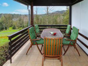 a wooden table and chairs on a porch with a view of the mountains at Holiday Home Kyjov u Krásné Lípy by Interhome in Kyjov