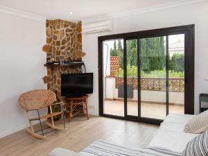 sala de estar con puerta corredera de cristal y TV en Apartment Adelfas by Interhome, en L'Escala
