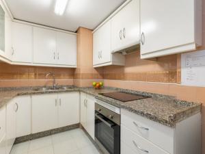 cocina con armarios blancos y encimeras de granito en Apartment Oasis by Interhome, en Torremolinos