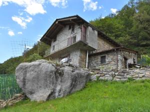 a stone house with a large rock in front of it at Chalet Rustico Rebustella by Interhome in Civo