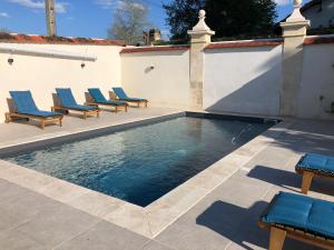 uma piscina com cadeiras azuis e uma parede em Hotel La Croix De Vernuche em Varennes Vauzelles