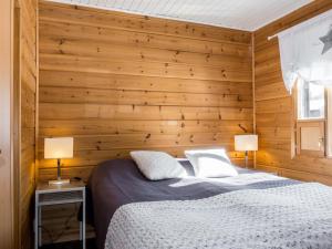 two beds in a room with wooden walls at Holiday Home Villa aihki by Interhome in Luosto