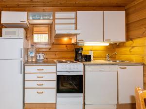 a kitchen with white appliances and wooden walls at Holiday Home Paapuuri by Interhome in Asikkala