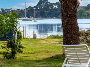 a white chair sitting next to a tree next to a lake at Apartment Le Moulin by Interhome in Saint-Philibert