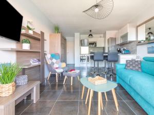 Una sala de estar con un sofá azul y una cocina. en Apartment Les Portes de Pyla by Interhome, en La Teste-de-Buch