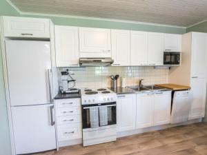 a kitchen with white cabinets and a white refrigerator at Holiday Home Tallbacka 2 by Interhome in Bromary