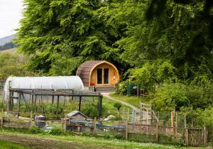 a barn with a building in the middle of a field at Glentruim Lodge Ecopod in Newtonmore