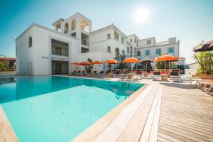a swimming pool in front of a building with orange umbrellas at Jazz Hotel in Olbia