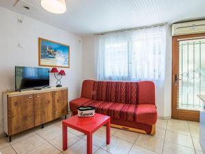 ein Wohnzimmer mit einem roten Sofa und einem TV in der Unterkunft Studio Le Grec by Interhome in Le Grau-du-Roi