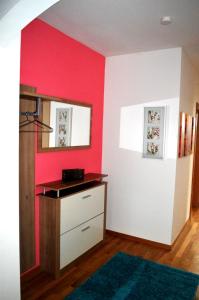 una habitación con una pared roja y un tocador en Ferienwohnung Schrittwieser, en Faak am See