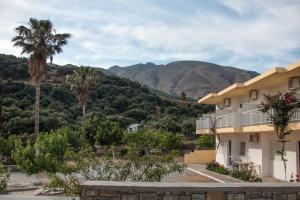 a building with palm trees and mountains in the background at Rykinthos studios in Rodakino