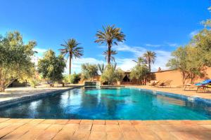 a swimming pool in a yard with palm trees at kasbah 123 soleil in Skoura