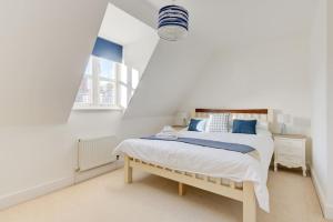 a white bedroom with a bed and a window at Juniper House in Harwich