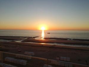 um pôr-do-sol sobre o oceano com uma praia em Genieten van de Vlaamse kust met prachtig zeezicht em De Haan