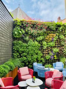 a patio with chairs and tables and a wall with flowers at Boutique Hotel Sablon in Bruges