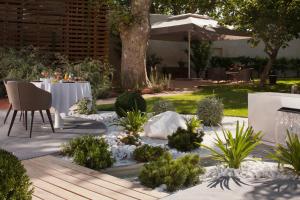 um jardim com uma mesa e cadeiras num quintal em Mas de Boudan em Nîmes