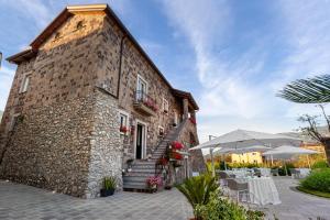 un edificio de piedra con un patio con mesas y sombrillas en Tenuta Miranda Agriresort en Pimonte
