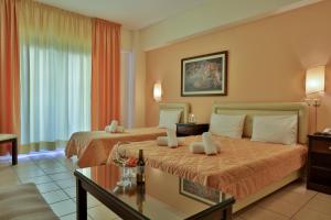 a hotel room with two beds and a table at Hotel Ilion in Paralia Katerinis