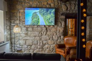 sala de estar con sofá y TV en una pared de piedra. en CAL MILIO, en Mayals