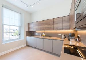 a kitchen with white cabinets and a large window at The New Town Idyll @ Dublin Street in Edinburgh