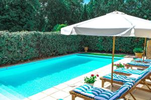 a swimming pool with two chairs and an umbrella at Logis hôtel et restaurant La Bastide Cabezac in Bize-Minervois