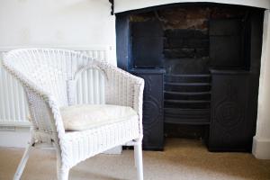 a white wicker chair sitting in front of a fireplace at The Grove Cromer in Cromer