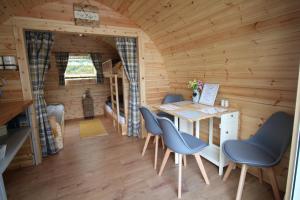 um quarto com uma mesa e cadeiras num chalé de madeira em Glamping Huts in Heart of Snowdonia em Dolgellau