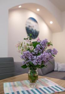 a vase of purple flowers sitting on a table at Apartament przy Parku in Duszniki Zdrój
