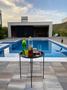 a table with two bottles and glasses on it next to a pool at Villa Una Residence in Bihać