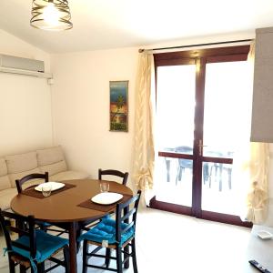 Appartamento Fonny Best Vacation Ever Villasimius في فيلاسيميوس: غرفة طعام مع طاولة وكراسي وأريكة