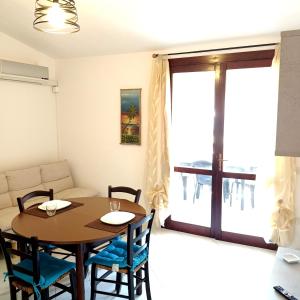 a dining room with a table and chairs and a couch at Appartamento Fonny Best Vacation Ever Villasimius in Villasimius