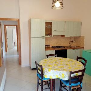 kuchnia ze stołem i krzesłami oraz kuchnia z białymi szafkami w obiekcie Appartamento Fonny Best Vacation Ever Villasimius w mieście Villasimius