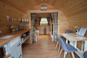 a kitchen and dining room of a log cabin with a table and chairs at Torrent Walk Glamping Huts in the Heart of Snowdonia in Dolgellau